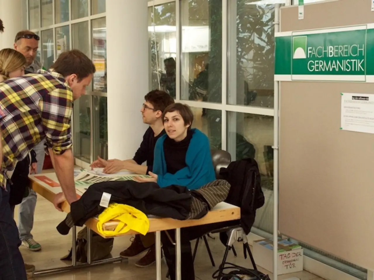 Here we see two people seated on a chair and few people are standing and speaking to them