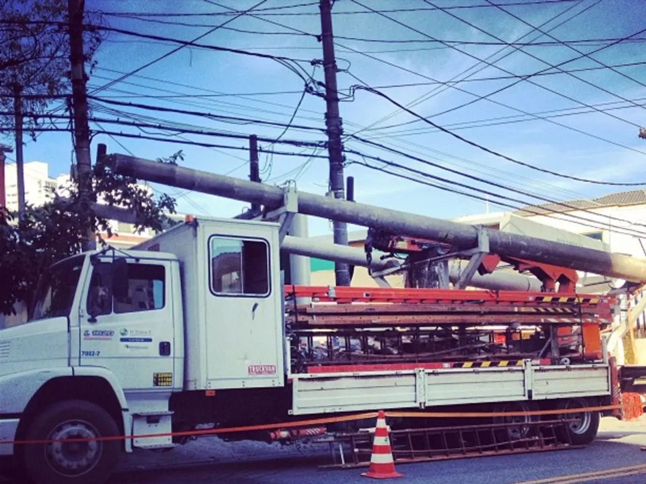 In this picture we can see a truck on the road with many machines, rods, equipment in it. In the...