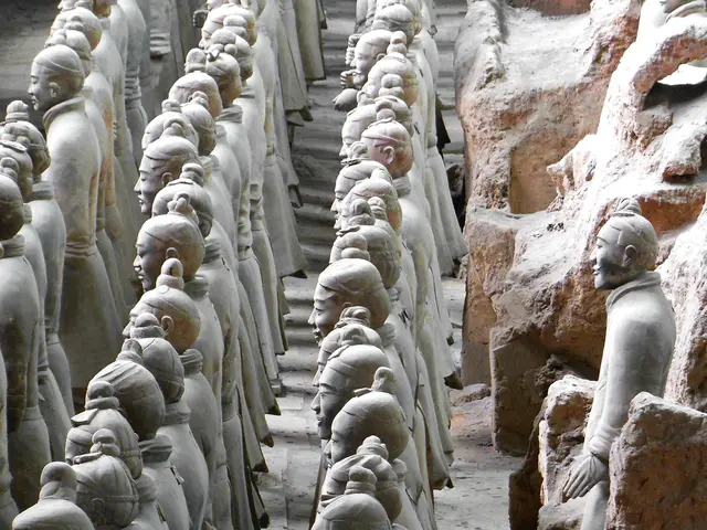 In this image there are many sculptures on the ground. To the right there are rocks.