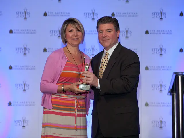 In this image I can see two persons standing and holding the trophy. The person at right is wearing...