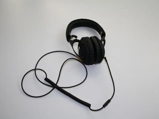 In this image I can see a black color headset placed on a white surface.
