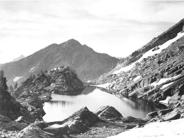 These are hills and we can see a small canal and some plants here and there on the hill.