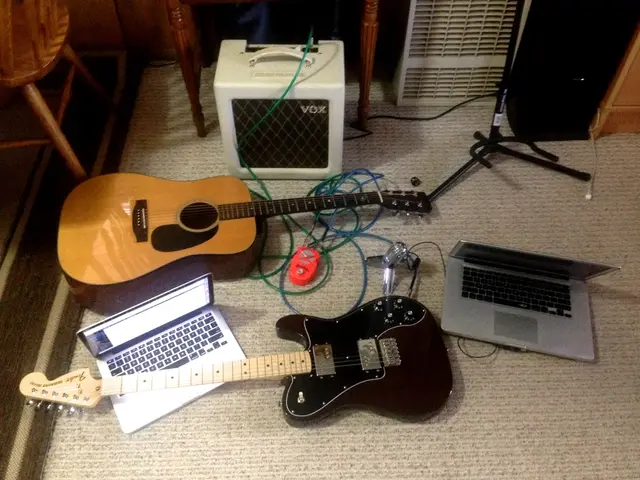 there are two guitar two laptops and two sound box on the floor.