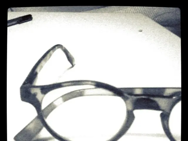In this picture we can see spectacles on white surface. Far there is a marker.
