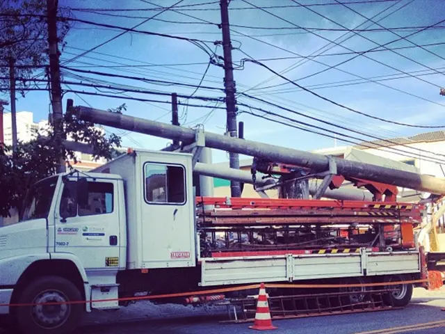 In this picture we can see a truck on the road with many machines, rods, equipment in it. In the...