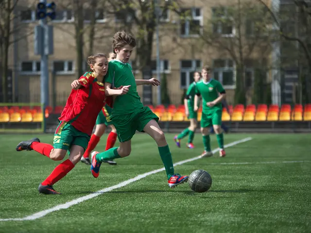 this picture shows few players playing football and we see trees around and a couple of buildings...