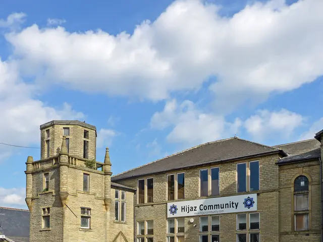 In the center of the image we can see the sky, clouds, buildings, windows, board with some text and...